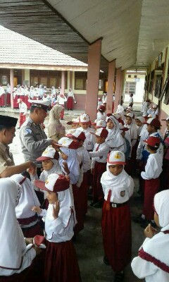 Kanit lantas polsek sungai apit didampingi guru saat bersalaman dengan murid-murid SDN 06 Kampung Kayu Ara usai upacara senin (7/3/2016).